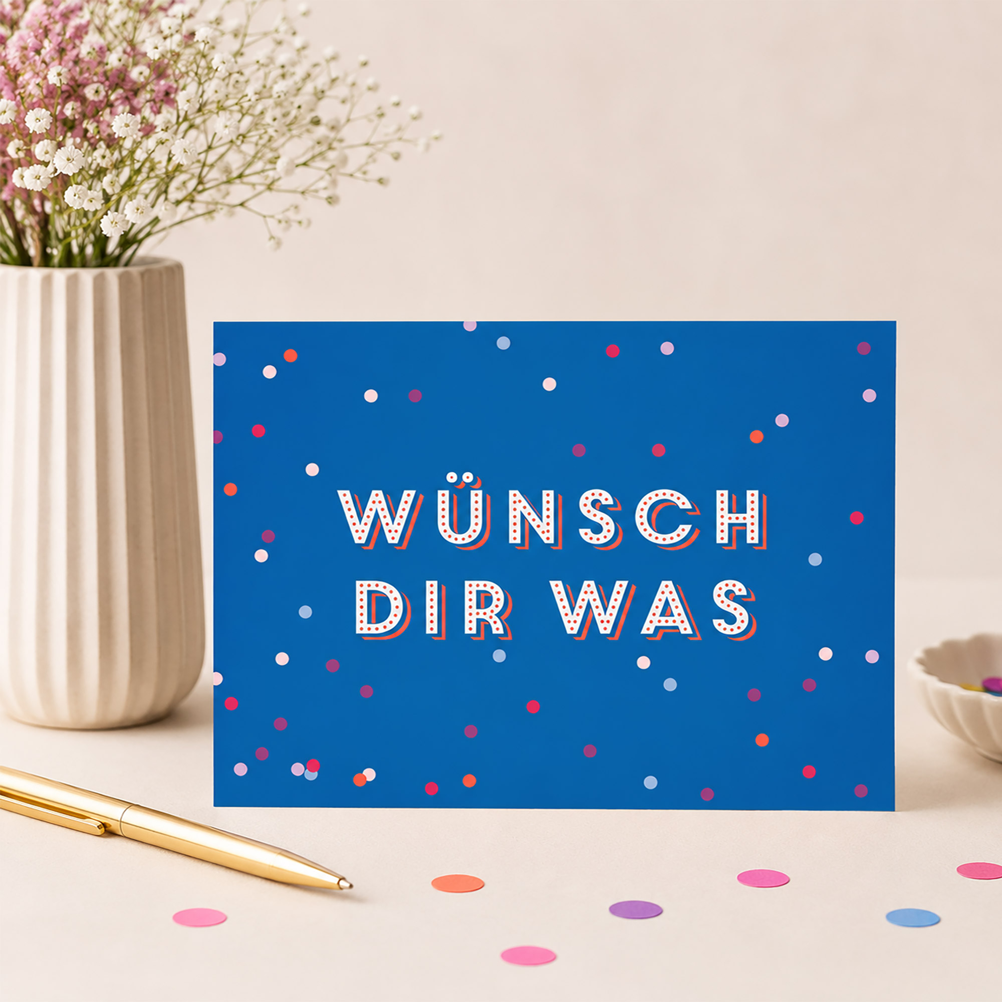 Blaue Postkarte zum Geburtstag mit dem Spruch „Wünsch dir was“ und bunten Konfetti-Punkten