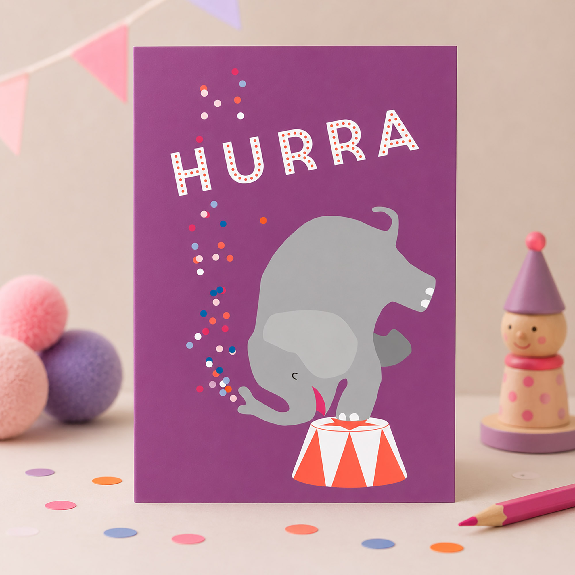Lila Glückwunschkarte mit dem Schriftzug „Hurra“, einem Elefanten auf einem Podest und bunten Konfetti-Punkten