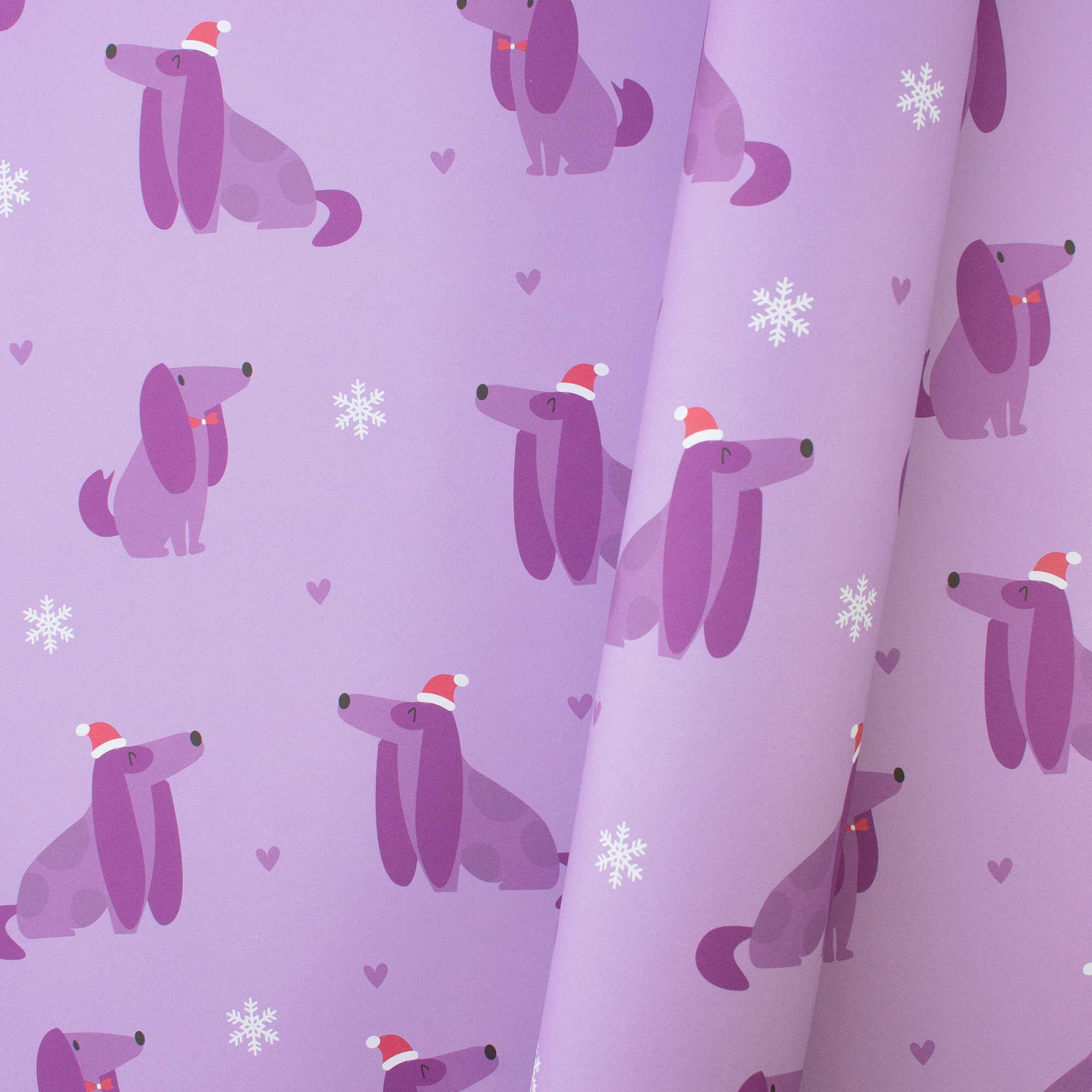 Teilweise eingerolltes Geschenkpapier „Christmas Dogs“ mit lila Hunden, Weihnachtsmützen, Herzen und weißen Schneeflocken auf Flieder.