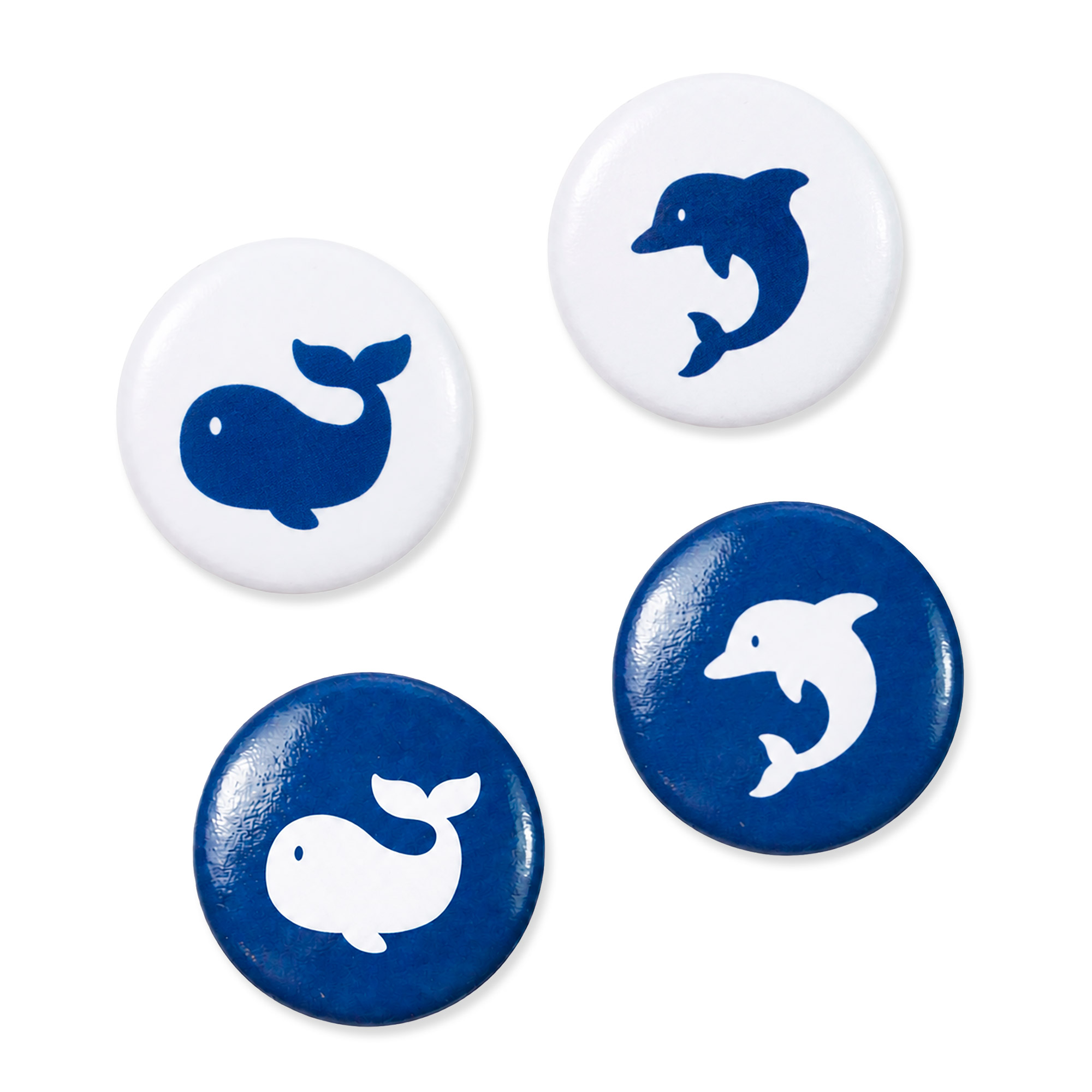 Vier runde Kühlschrankmagnete mit Wal- und Delfinmotiven in Blau auf Weiß und Weiß auf Blau, locker auf weißem Hintergrund angeordnet.
